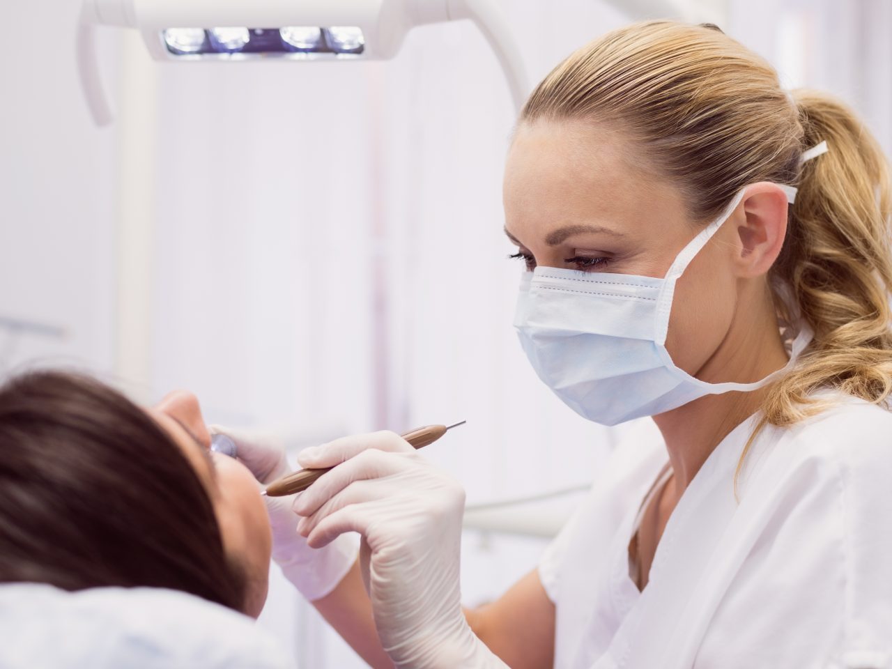 Dentist examining female patient in clinic